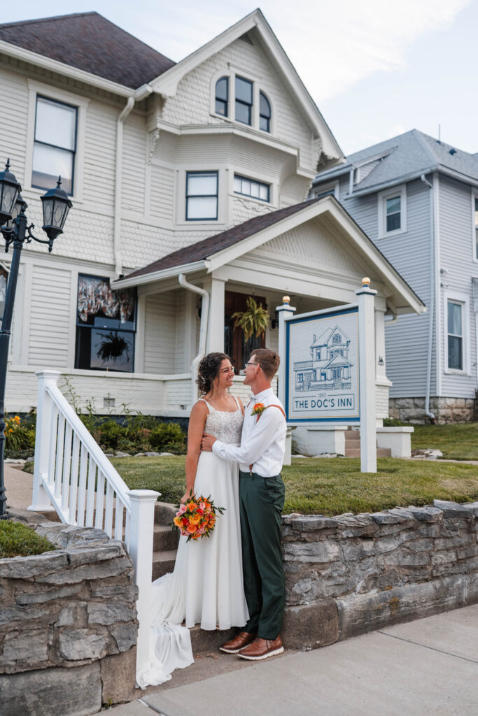 Bride and Groom smiling in front of The Doc's Inn in Greencastle, Indiana.