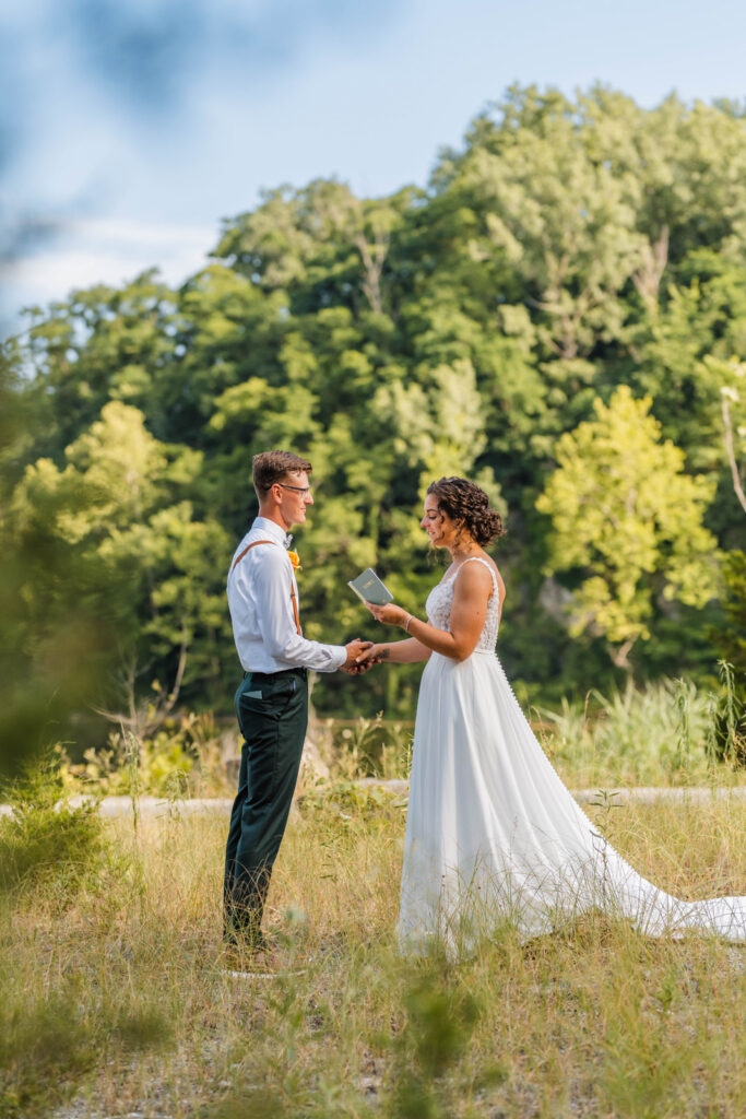 Bride reads vows from her vow book during elopement ceremony at DePauw Nature Park.