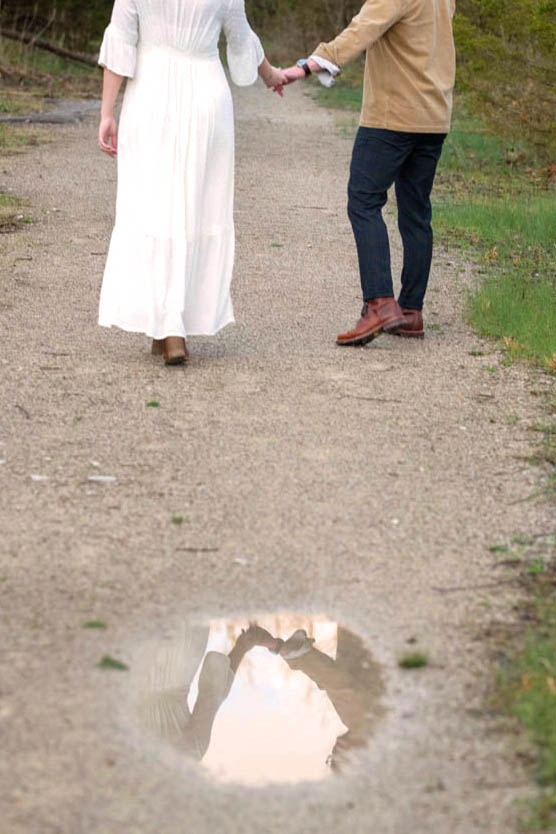 Couple's reflection in a puddle shows them holding hands.