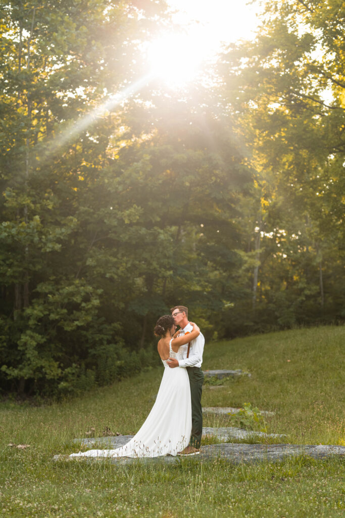 Bride and groom share their first dance during their elopement with the sun shining above them at DePauw Nature Park.