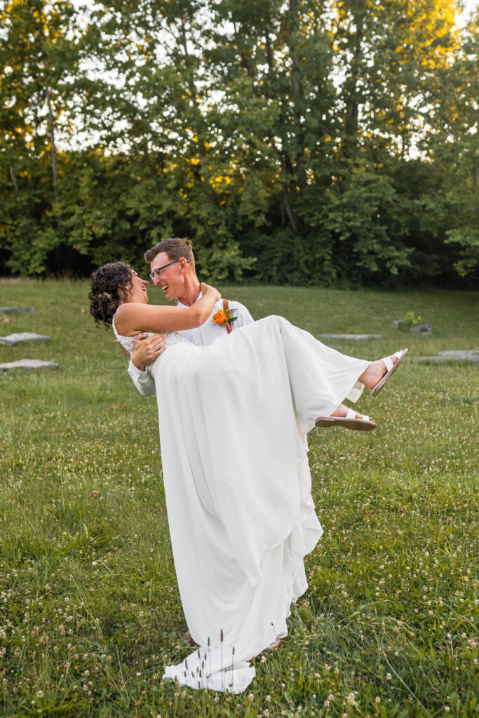 Groom picks up bride and they laugh together.