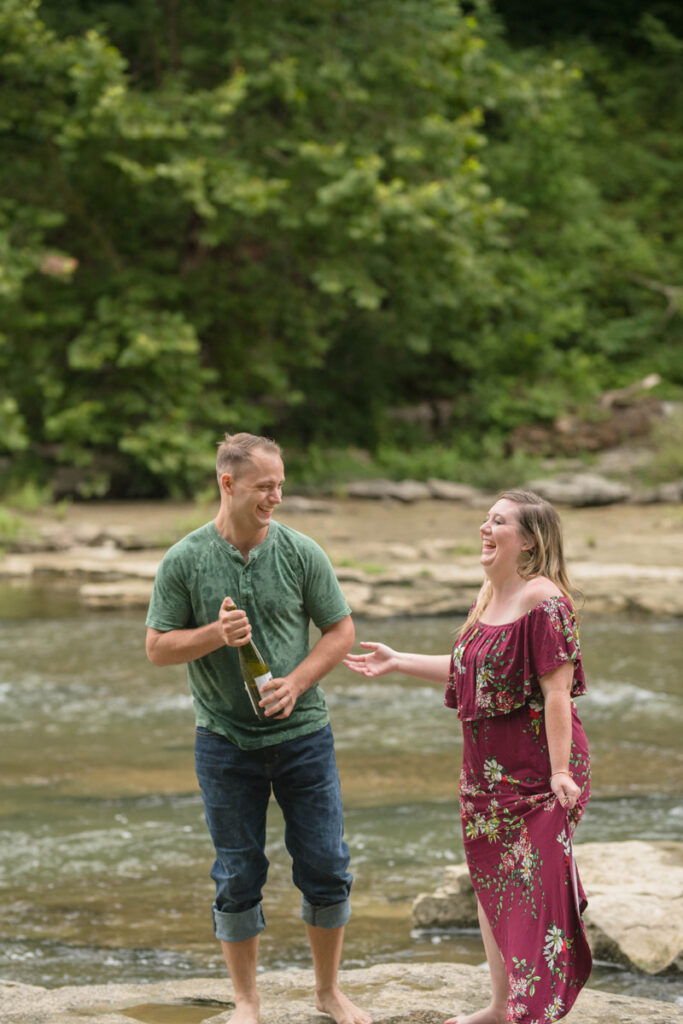 Couple laughs before they shake sparkling water bottle.