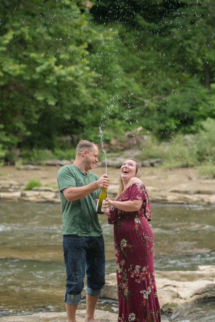 Lots of laughter from couple doing a sparkling water pop standing in stream.