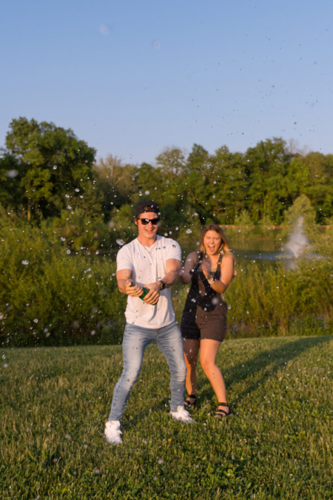 Water droplets in focus as couple sprays sparkling water at sunset.