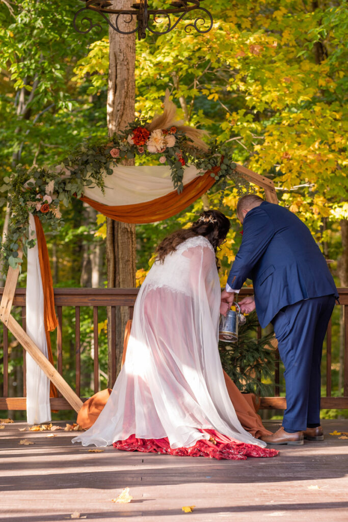 Bride and groom water small evergreen tree as part of their unity ceremony at wedding as a sustainable alternative.