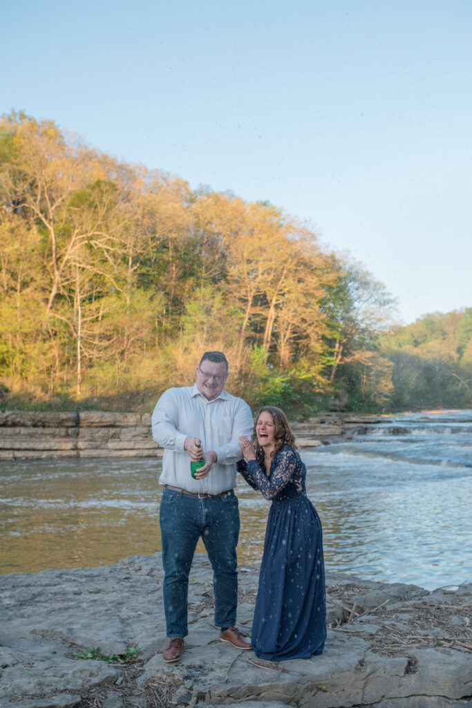 Newly engaged couple spray sparkling water after proposal.