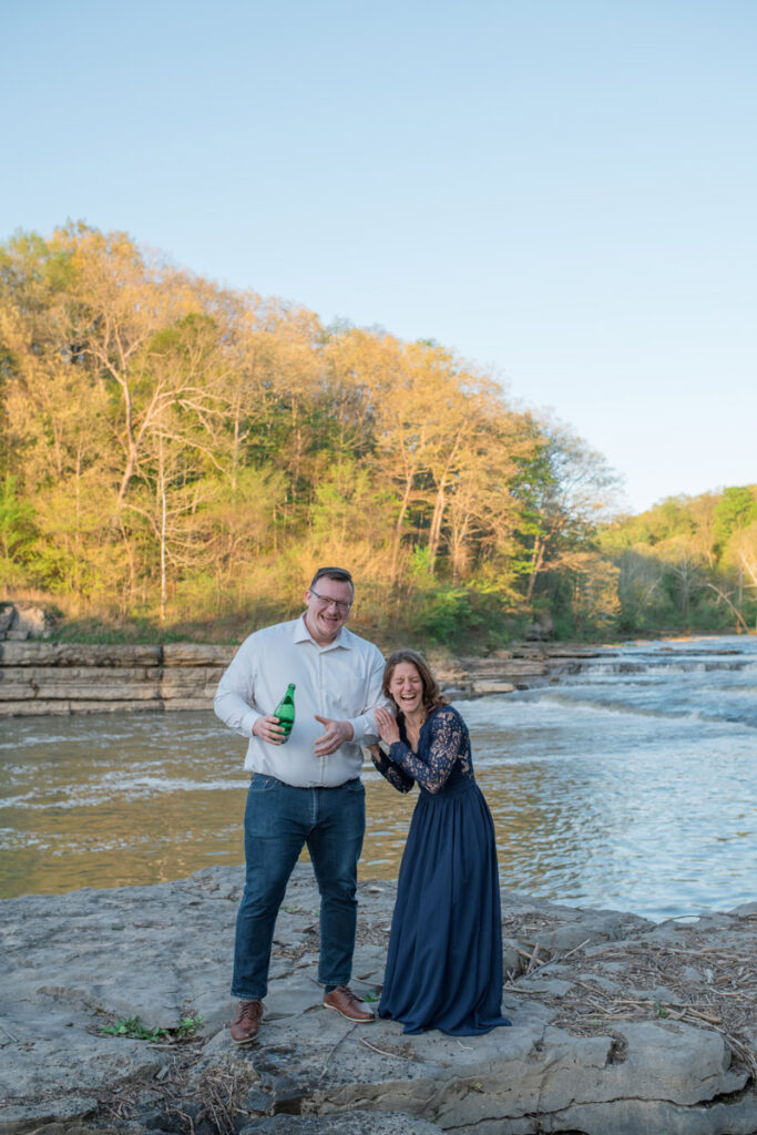 Man and woman laugh after they spray sparkling water everywhere.