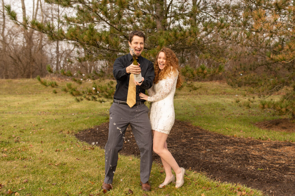 Couple dressed up sprays sparking water while laughing.