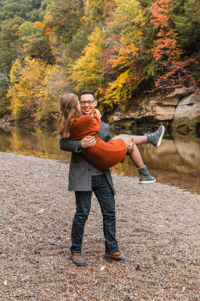 Guy picks up girl next to a creek to spin her around.