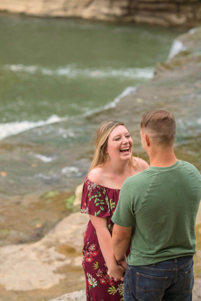 Couple laughing near water.