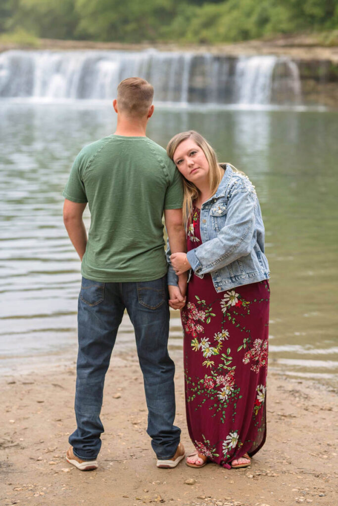 Couple holds hands in front of waterfall at Cataract Falls.