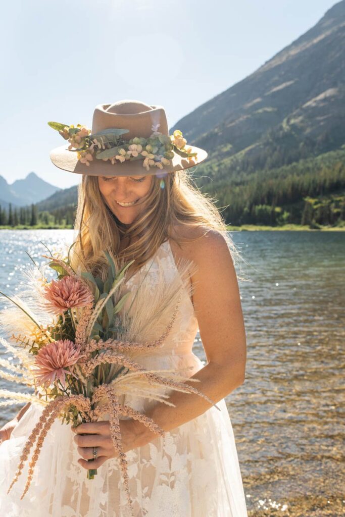 Bride holds her flowers while standing in front of lake at Glacier National Park Elopement.