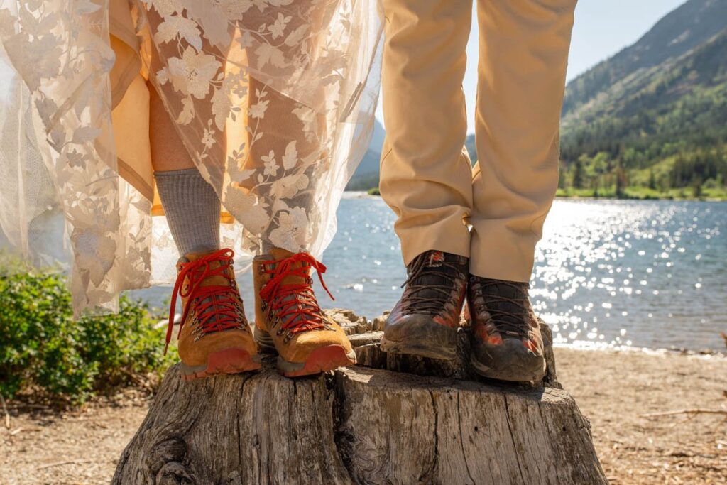 Bride and groom wearing hiking boots while standing on a stump.