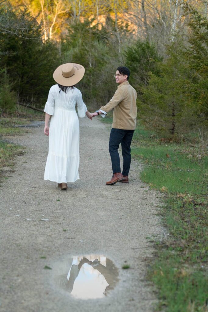 Bride and groom hold hands at their elopement and reflection of their hands shows in puddle.