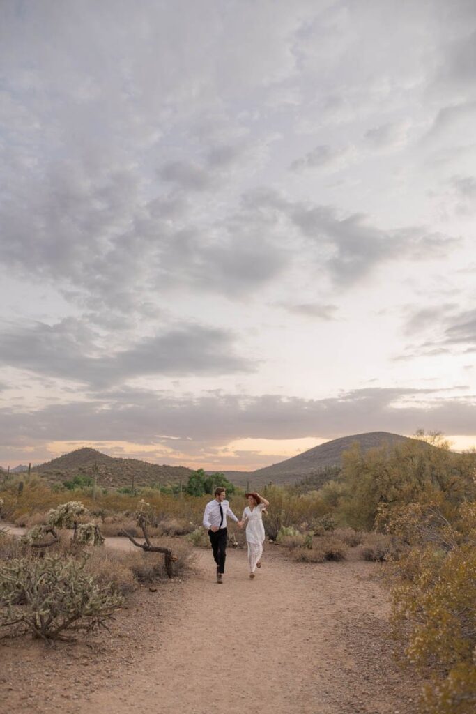 Bride and groom running in the dessert after they elope.
