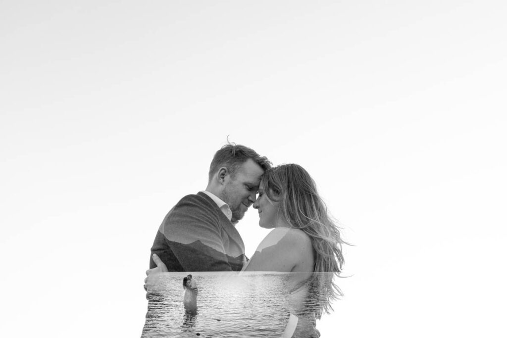 Double exposure of a couple embracing with an image of themselves standing in a lake kissing.