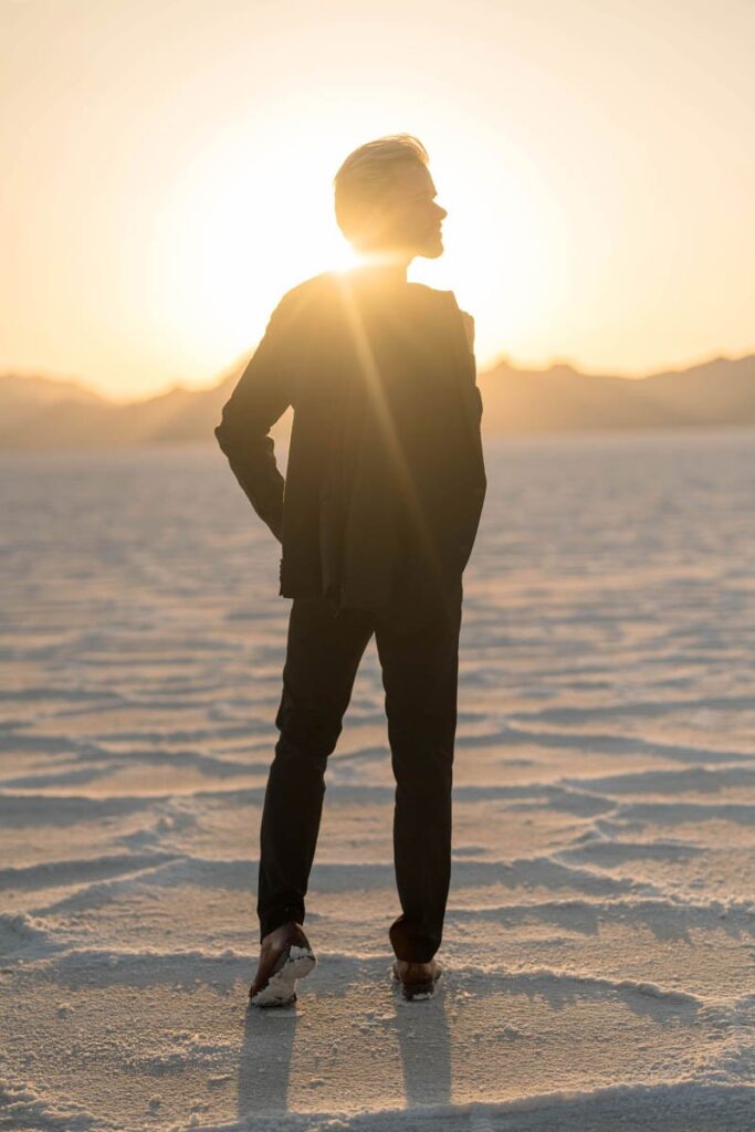 Groom stands looking away at sunset in the Salt Flats of Utah.