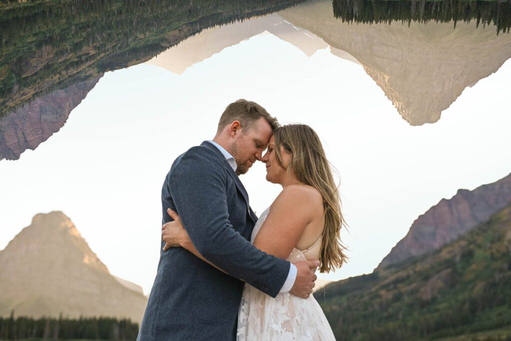 Couple hold each other close with mountains around them and double exposure of mountains above them.
