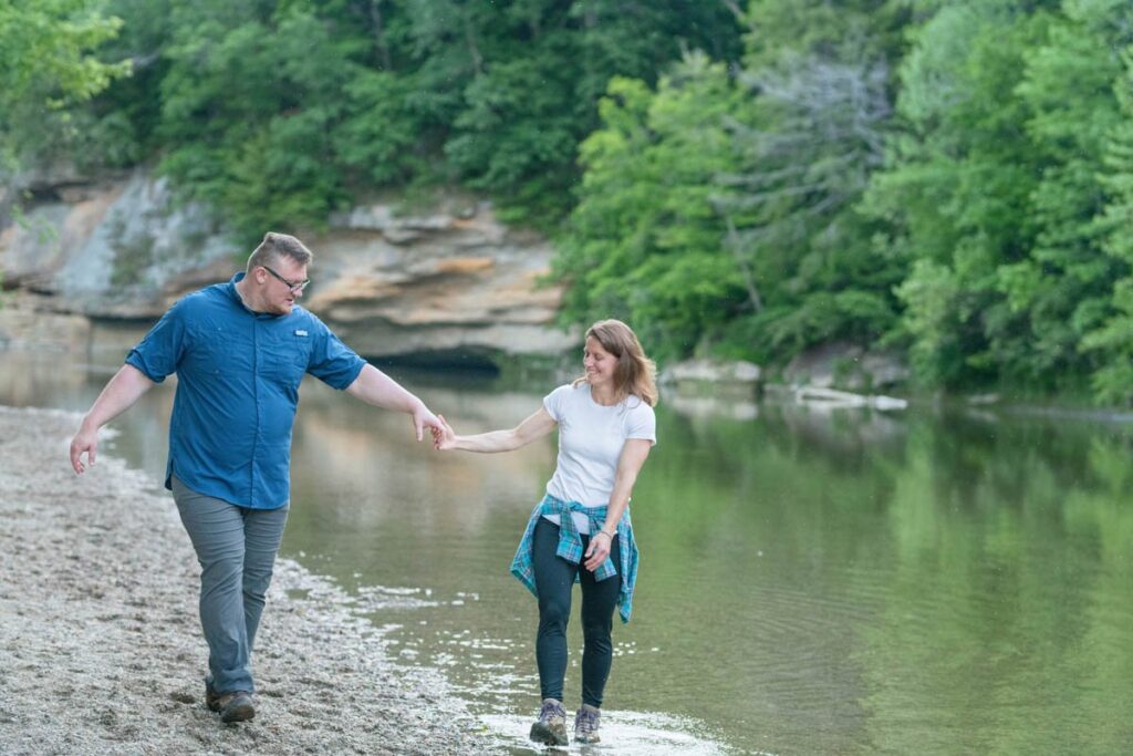 Couple has fun walking next to a creek together holding hands.