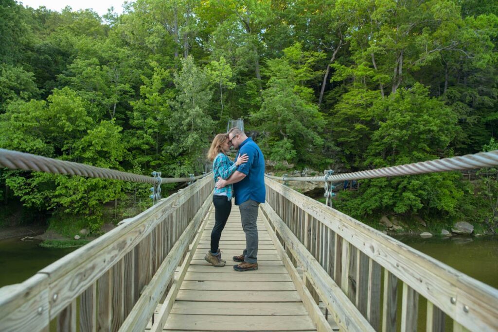 Couple hold one another on suspension bridge while hiking at Turkey Run State Park in Indiana.