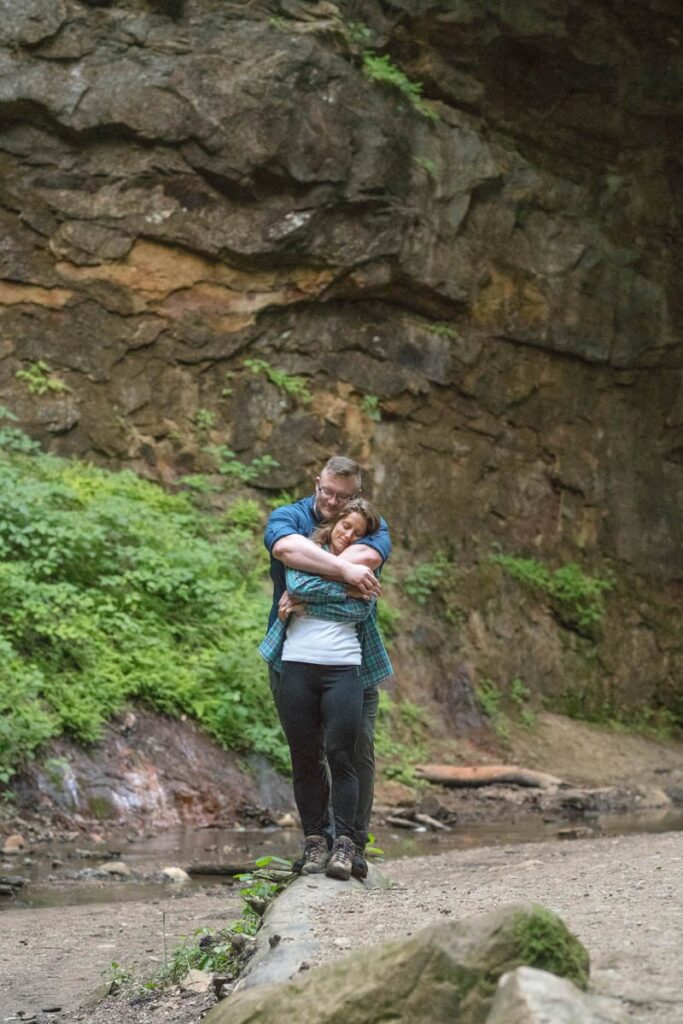 Couple hugs while standing on a log.