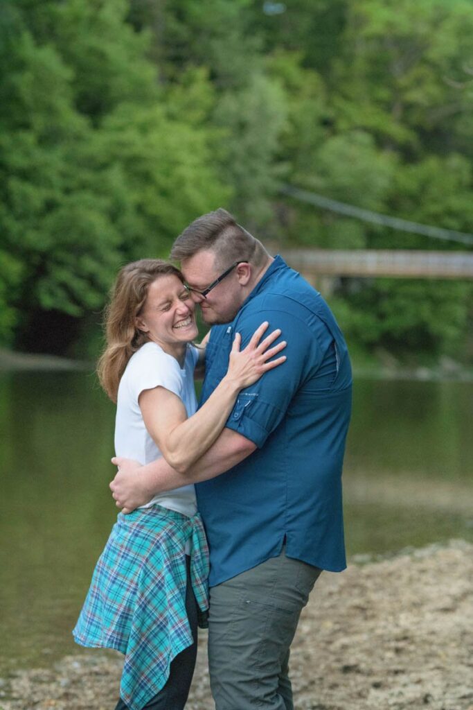 Man makes woman laugh while touching his nose to her cheek.