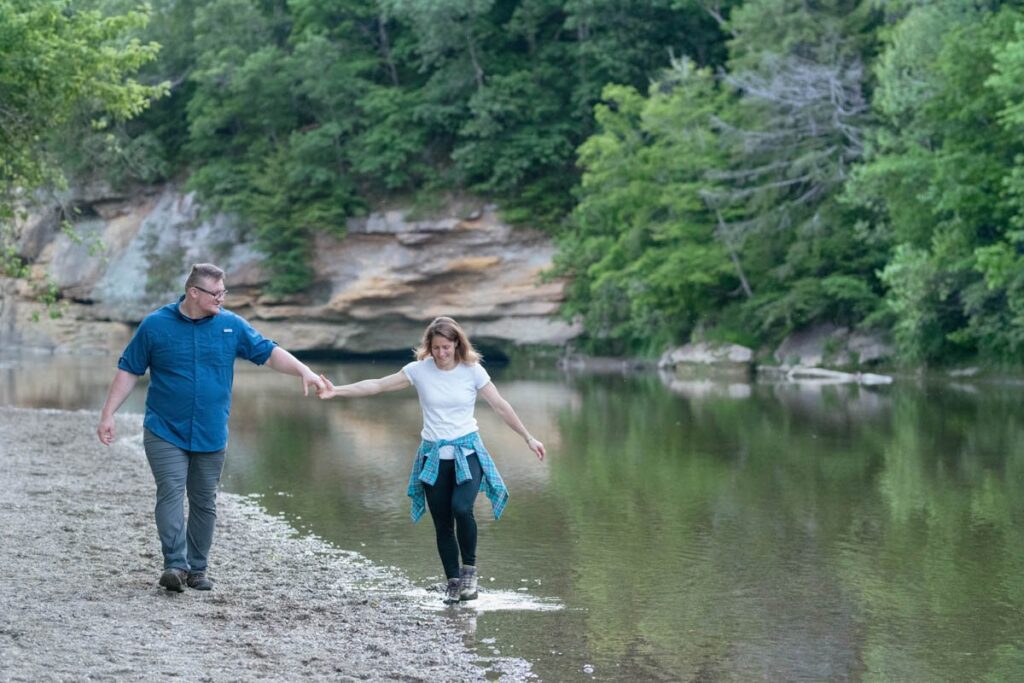 Man and woman hold hands and happily walk in the creek at Turkey Run State Park in Indiana.