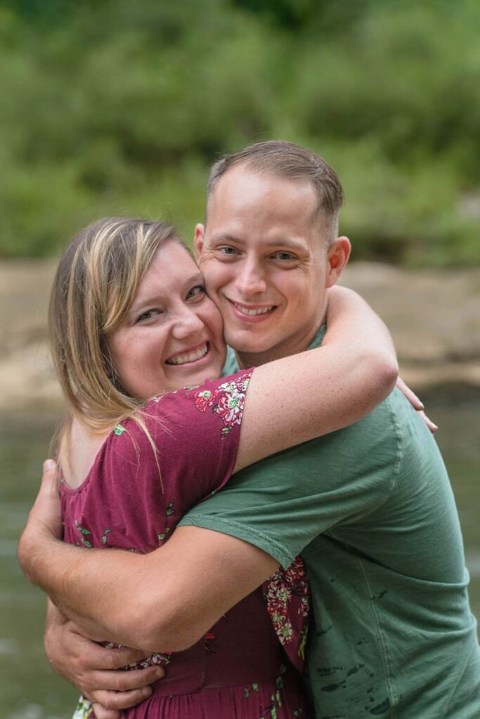 Couple smiles while giving each other a big hug.