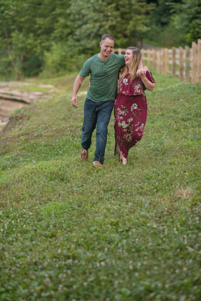 Couple is walking through the grass and laughing together.