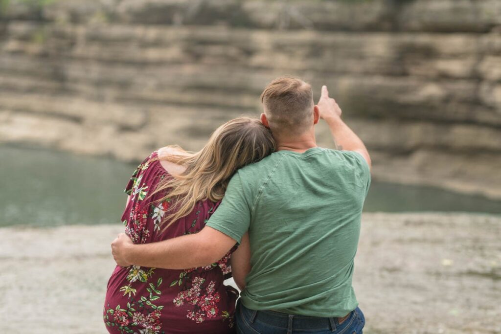 Man points while couple looks over Cataract Falls at sunset.