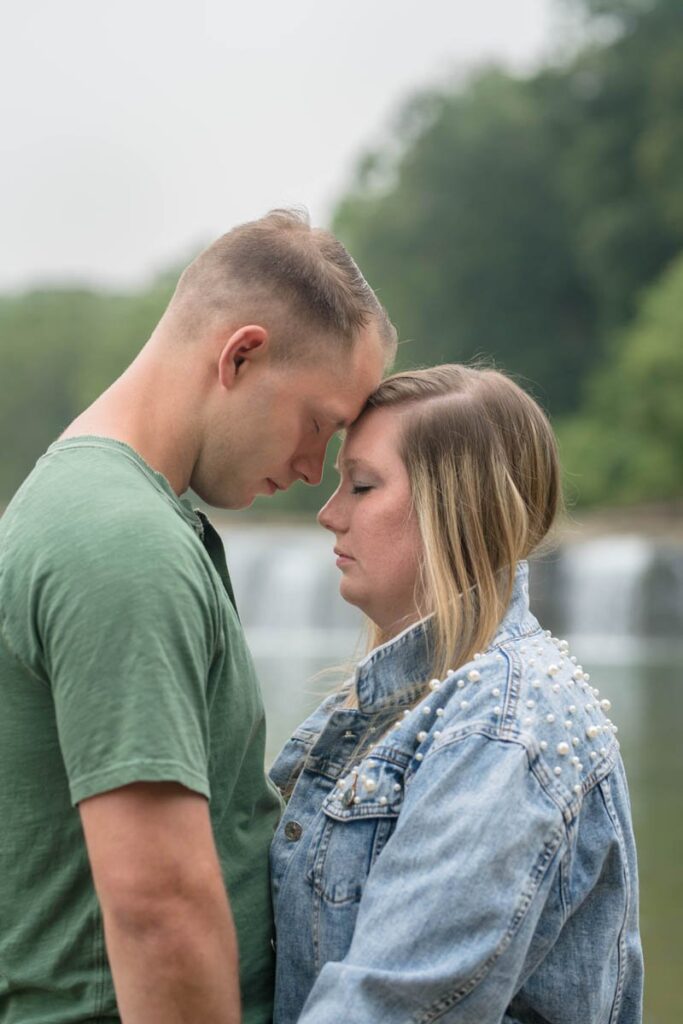 Couple rests their foreheads against each other in front of Cataract Falls.