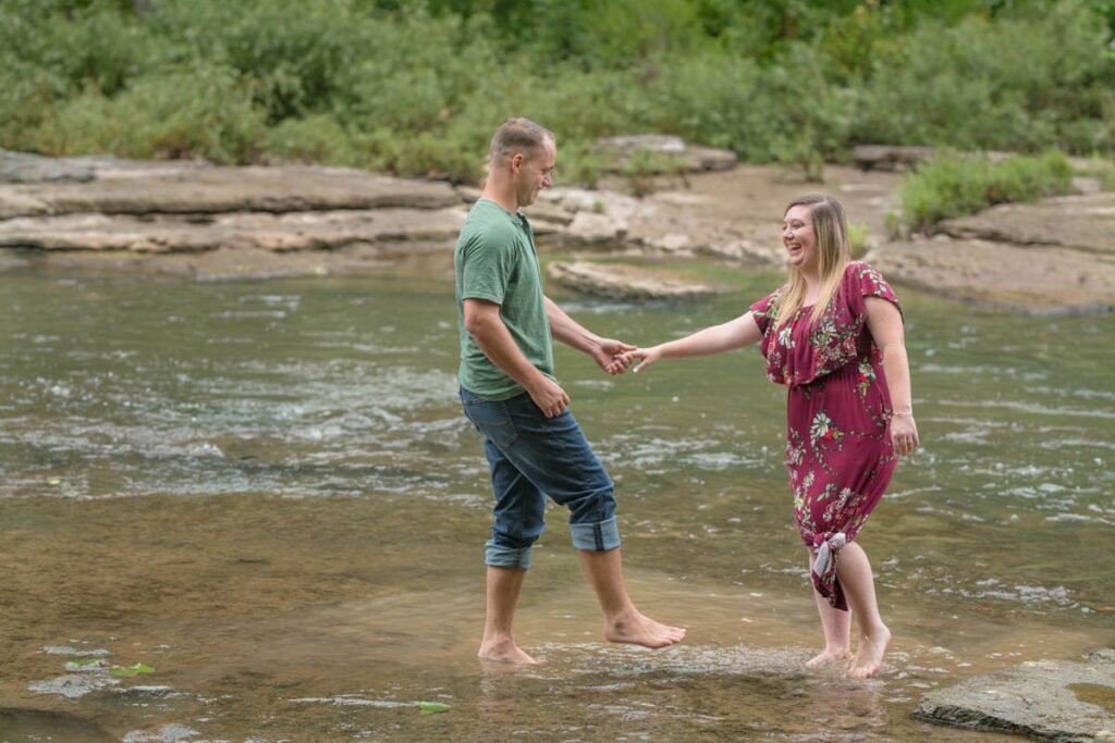 Couple plays barefoot in the water at Cataract Falls for their waterfall engagement photos.