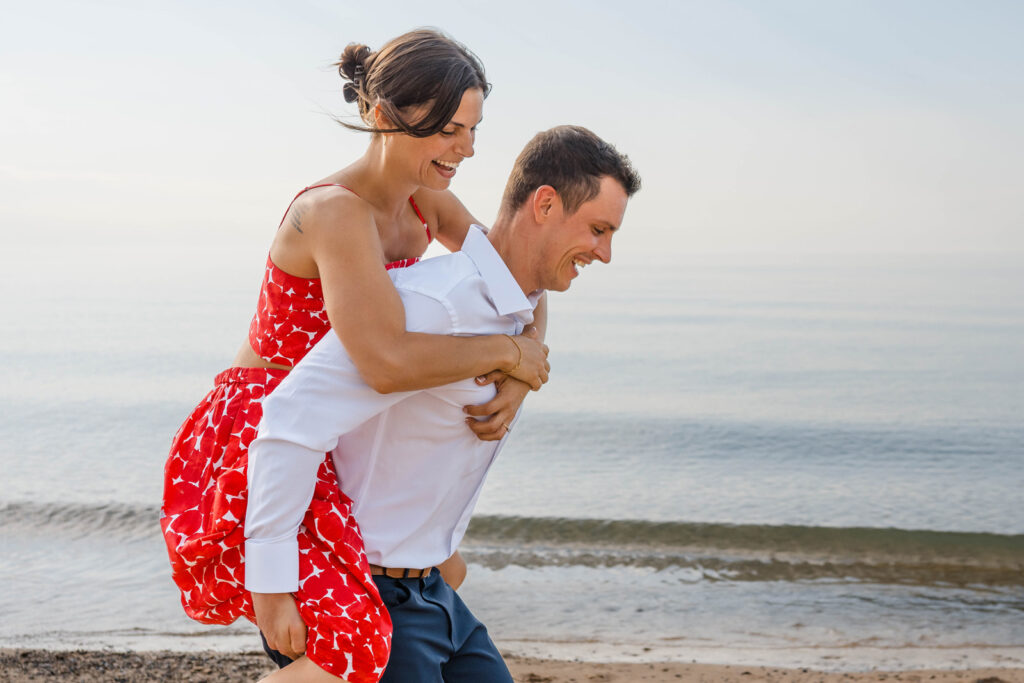 Guy gives girl a bumpy piggyback ride along the lakeshore at Indiana Dunes.
