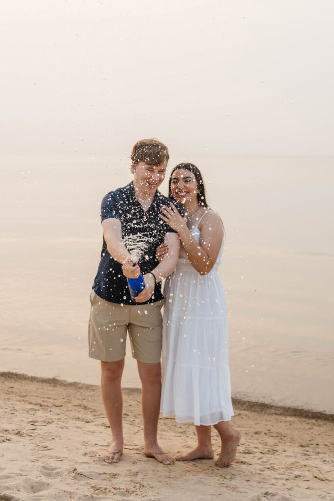 Couple pops sparking water during their beach engagement photos.