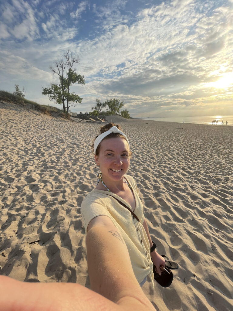 Girl smiling while walking in the sand at sunset.