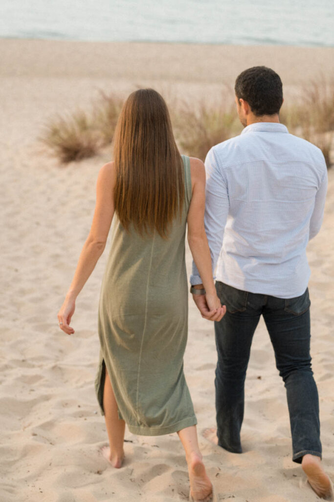 Couple walks hand in hand on the beach.