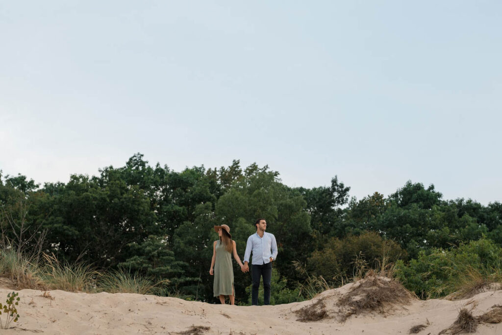 Couple stands on top of a sand dune during their beach couples photos at Indiana Dunes.