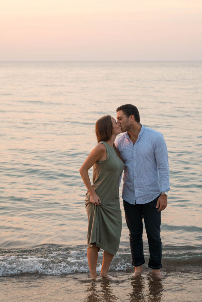 Couple wades and stands in the water kissing.