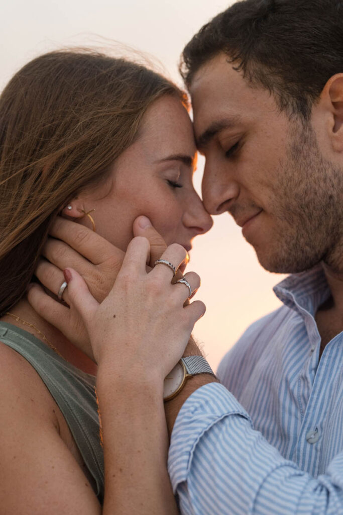 Man holds woman's face to his while they have their eyes closed.