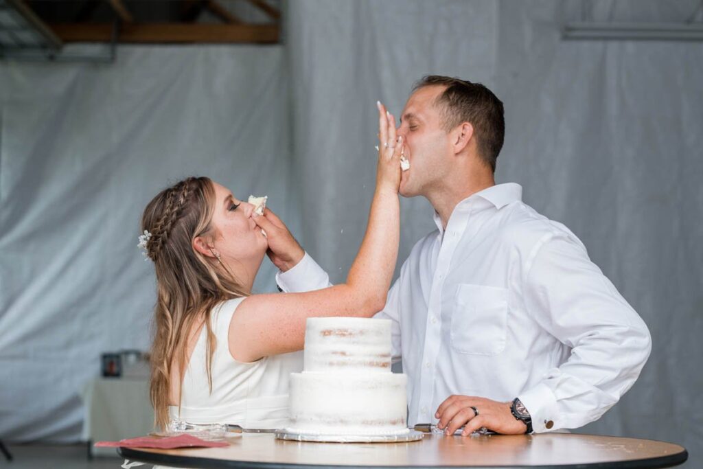 Bride and groom smash cake into one another's mouths.
