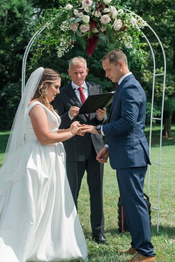 Bride and groom exchange rings during their Indiana outdoor wedding ceremony.