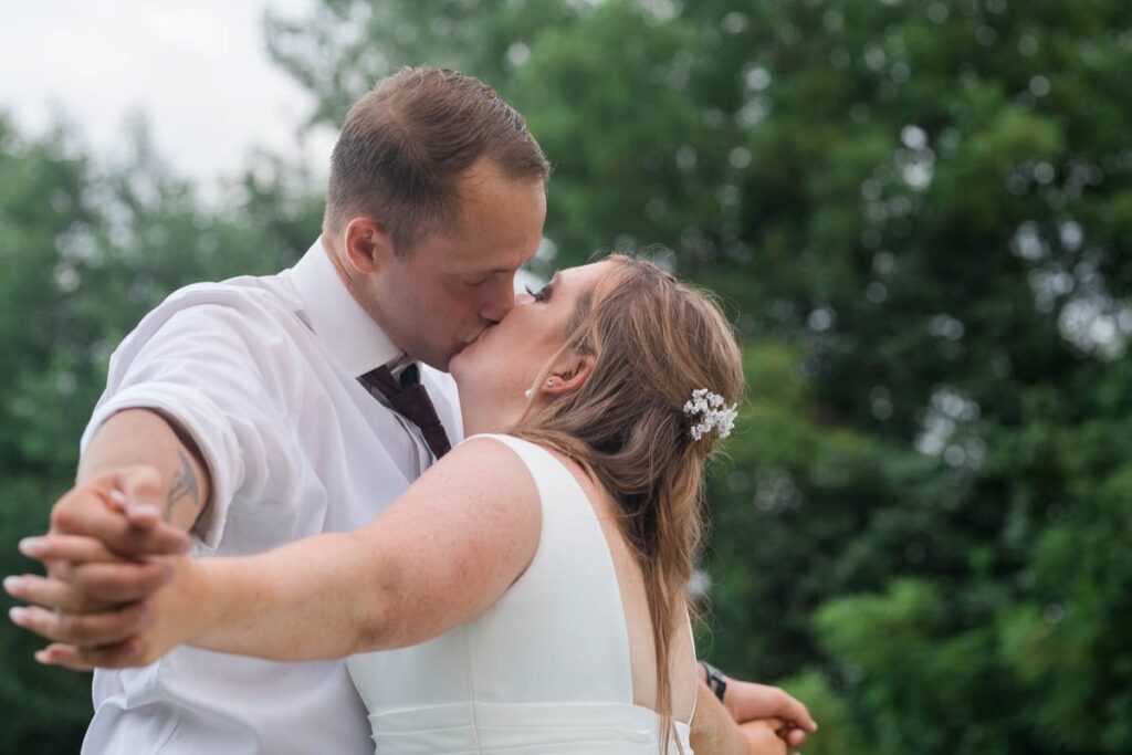 Bride and groom kiss with their fingers interlaced.