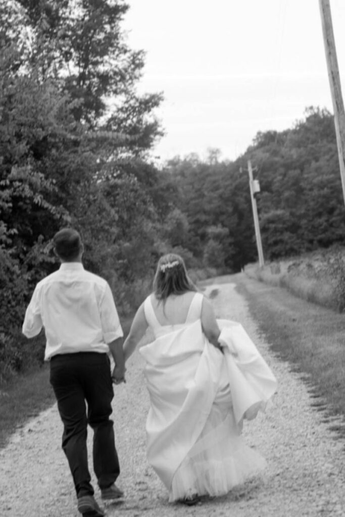 Bride and groom are blurry as they run down a gravel road holding hands.