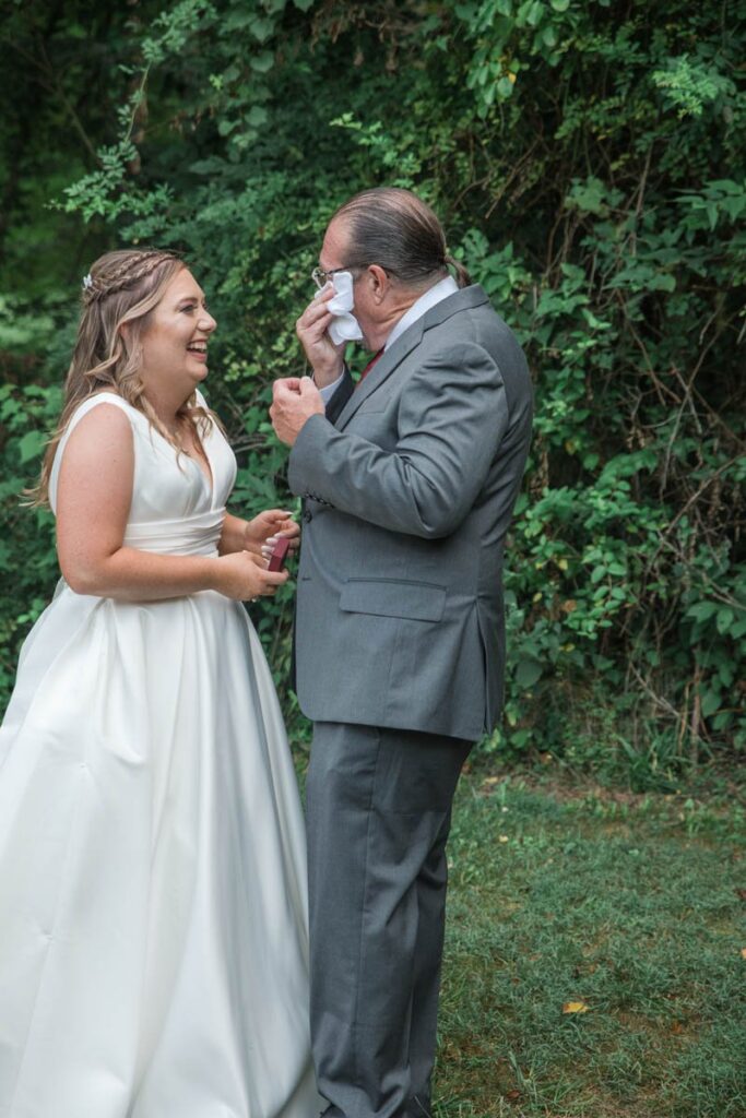Father of bride wipes his eyes with handkerchief.