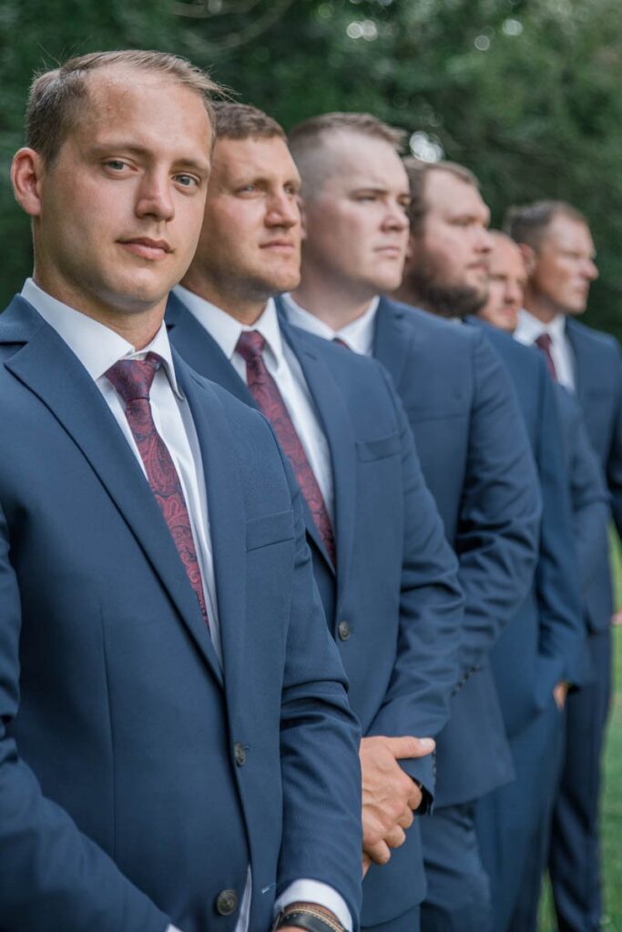 Groom and groomsmen being serious for portrait with only the groom in focus.