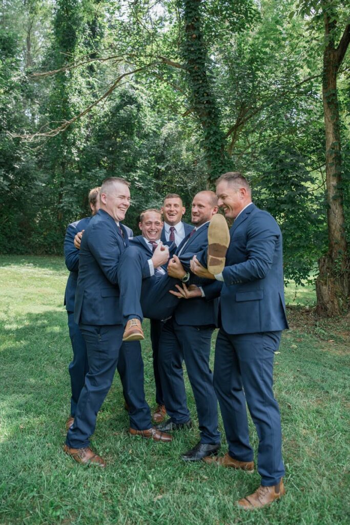 Groomsmen hold groom after tossing him into the air.