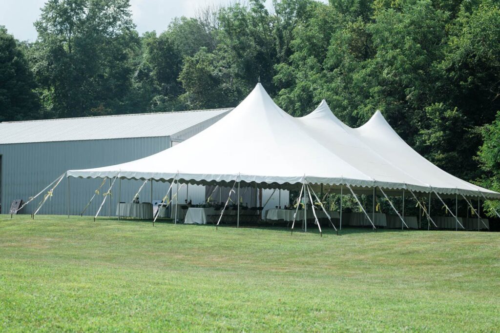Outdoor wedding reception tent with tables and twinkle lights.
