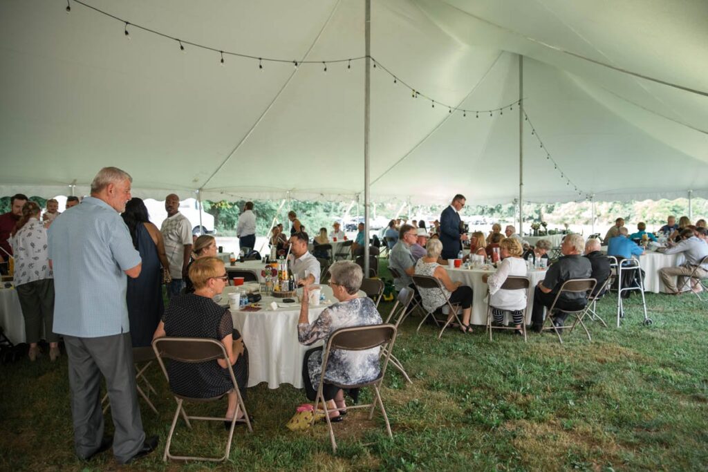 Guests mingling in reception tent at an Indiana outdoor wedding.