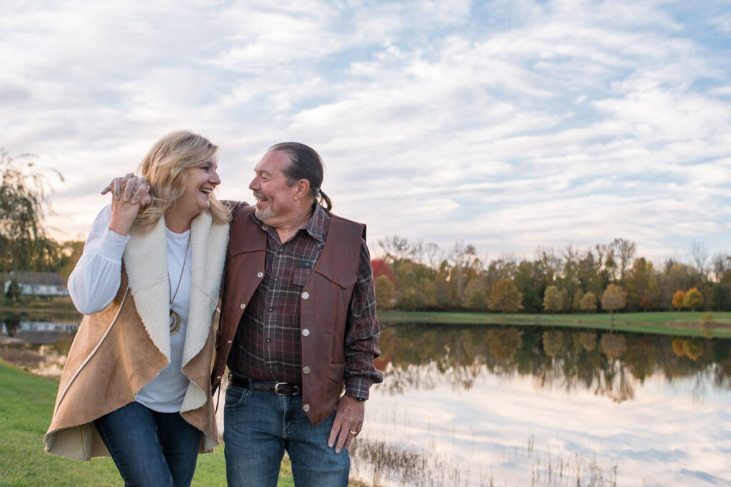 Woman and man smile at one another as they walk next to Blue Heron Lake at sunset.