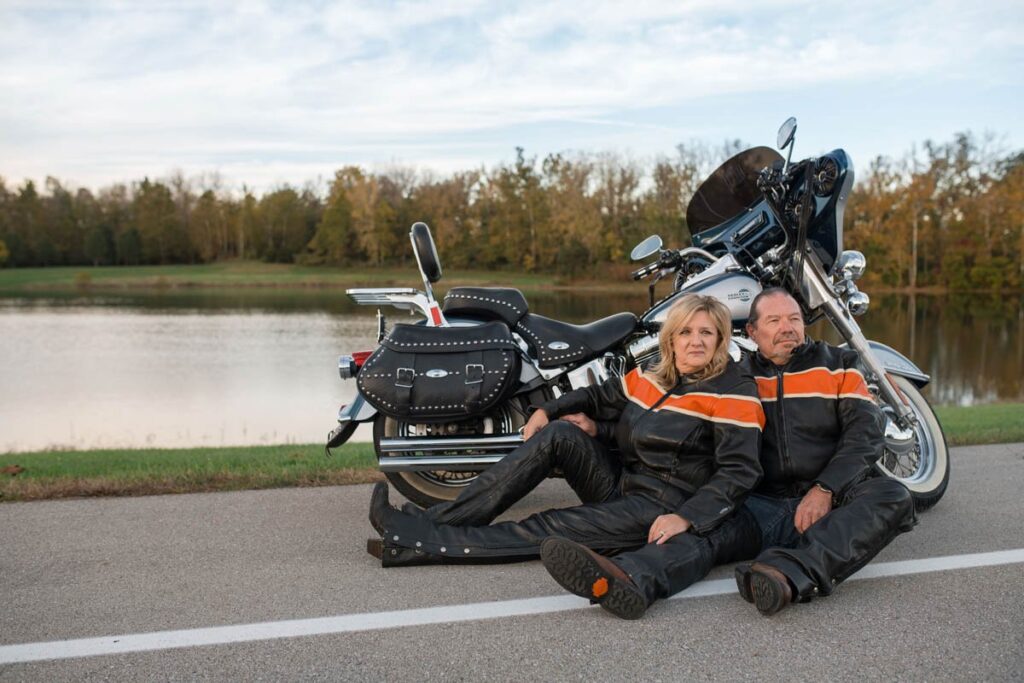 Husband and wife sitting in front of their Harley during a couples photography session.